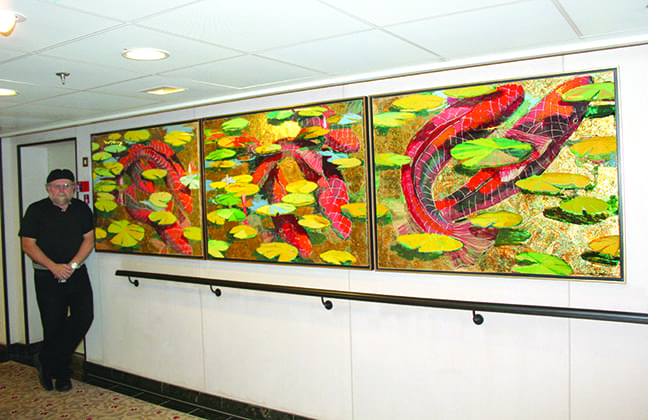 Frank displaying a triptych of 3 fish paintings.